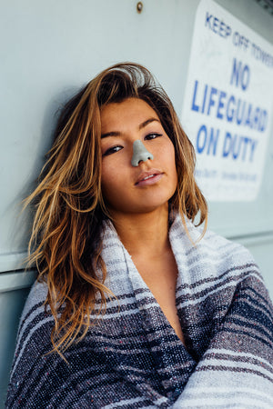 Woman with brown hair wearing Nöz's environmentally safe nose sunscreen in the color blue.